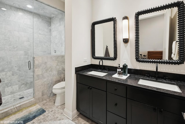 bathroom featuring double vanity, a stall shower, a sink, and toilet