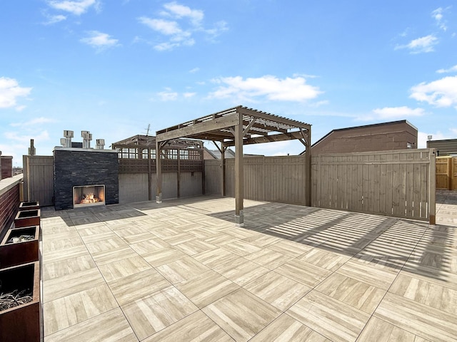 view of patio with a warm lit fireplace, fence, and a pergola