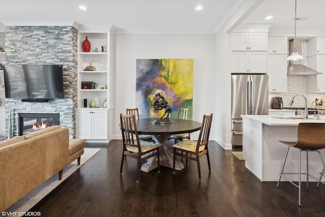 dining area with dark wood-style floors, ornamental molding, a fireplace, and baseboards