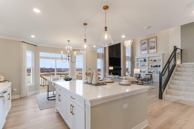 kitchen featuring a kitchen island, white cabinets, open floor plan, light countertops, and decorative light fixtures