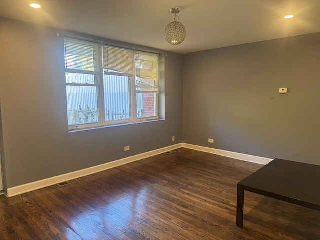 empty room featuring dark wood-style floors, recessed lighting, visible vents, and baseboards