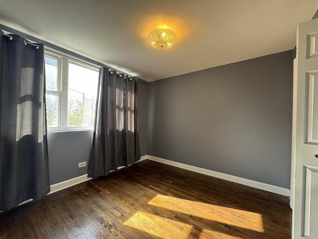 empty room featuring baseboards and dark wood-style flooring