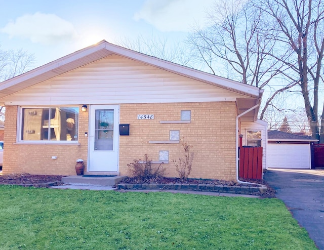 view of front facade featuring a garage, a front yard, an outbuilding, and brick siding