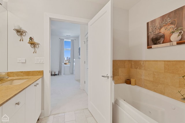 bathroom with a jetted tub, tile patterned flooring, and vanity