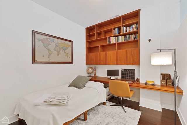 bedroom featuring built in desk, dark wood finished floors, visible vents, and baseboards