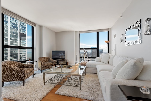 living area with expansive windows, visible vents, and wood finished floors