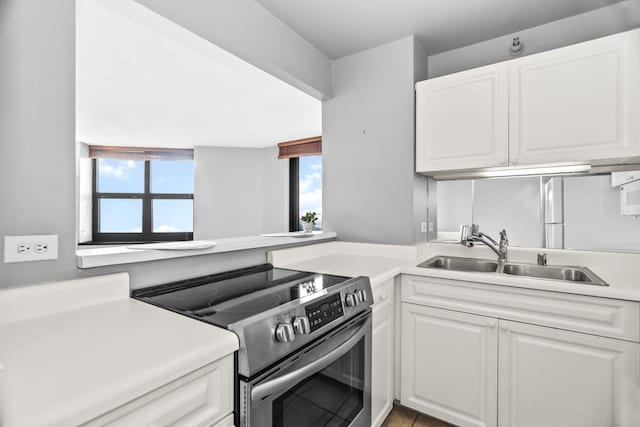 kitchen with a sink, white cabinetry, light countertops, and electric stove