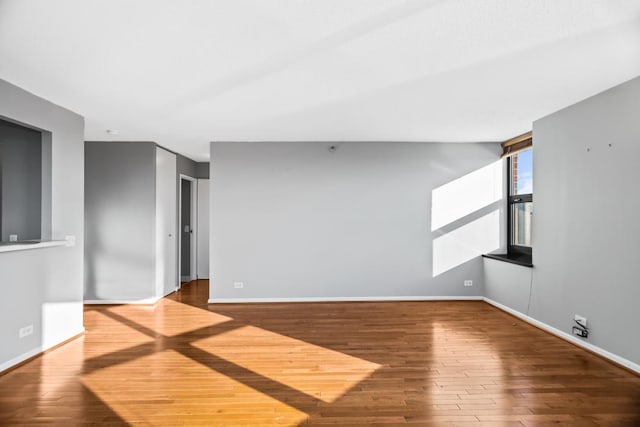 unfurnished room featuring hardwood / wood-style flooring and baseboards