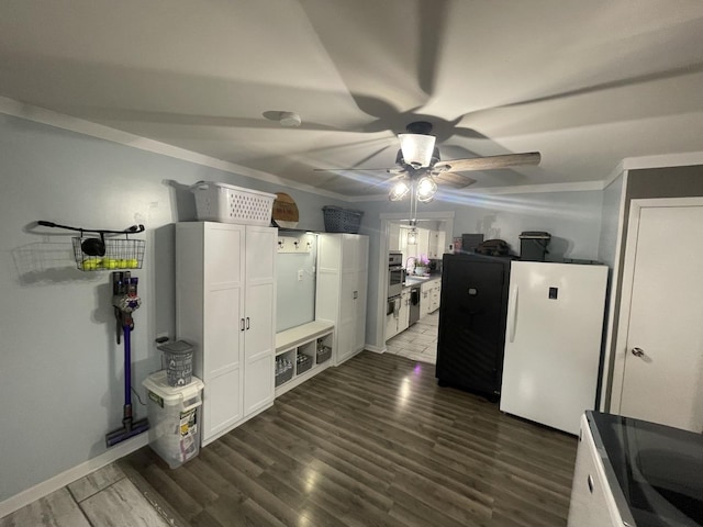 kitchen with dark wood finished floors, a ceiling fan, ornamental molding, freestanding refrigerator, and white cabinetry