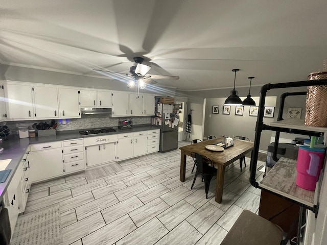 kitchen featuring dark countertops, freestanding refrigerator, white cabinets, and under cabinet range hood