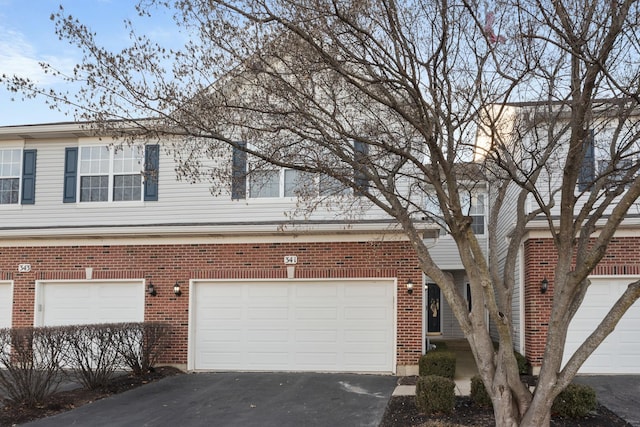 exterior space featuring a garage, driveway, and brick siding