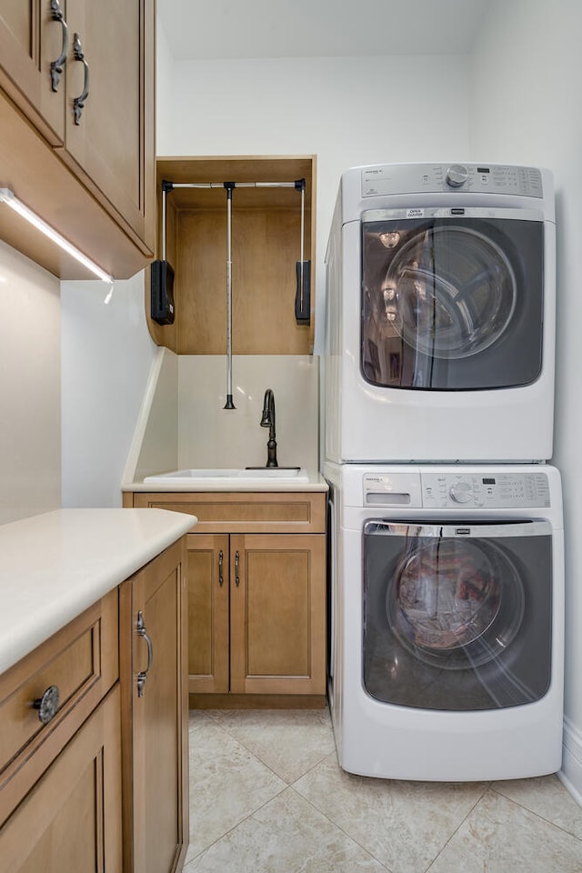 washroom featuring light tile patterned flooring, a sink, cabinet space, and stacked washer / drying machine