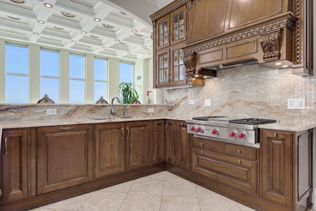 kitchen featuring backsplash, a sink, light stone countertops, stainless steel gas cooktop, and beam ceiling