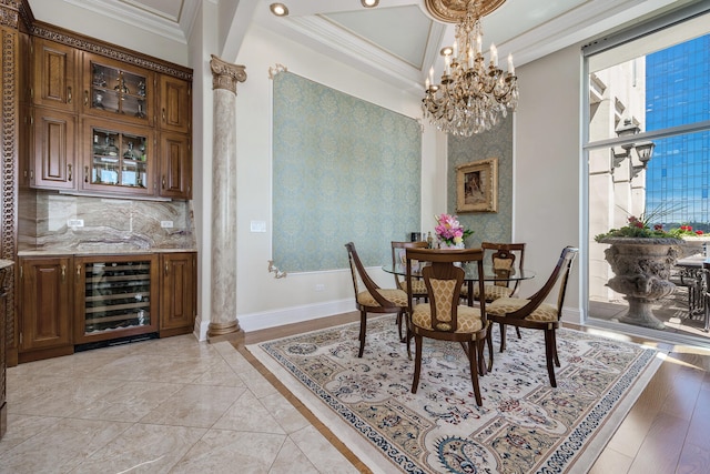 dining room with a notable chandelier, beverage cooler, baseboards, ornamental molding, and ornate columns