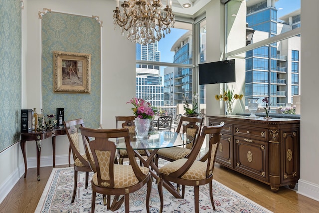 dining space with light wood-type flooring, wallpapered walls, baseboards, and a notable chandelier