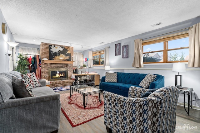 living area with a brick fireplace, a textured ceiling, and light wood finished floors