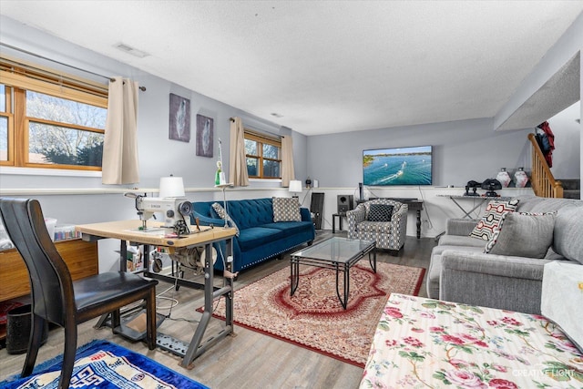 living room featuring visible vents, a textured ceiling, and wood finished floors