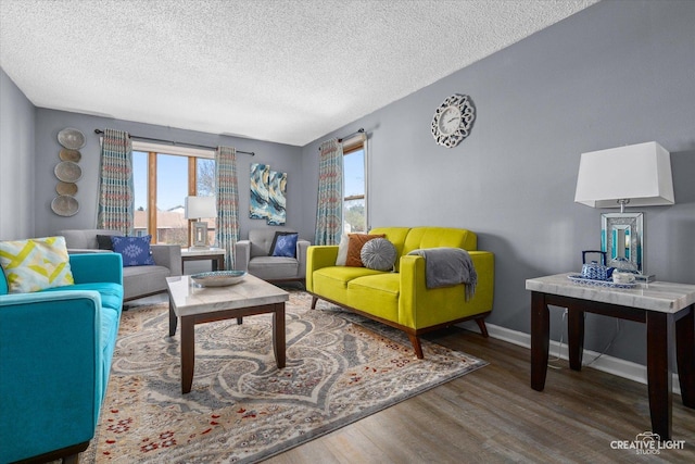 living area featuring a textured ceiling, baseboards, and wood finished floors