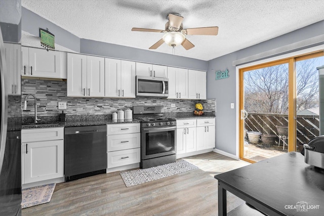 kitchen with stainless steel appliances, tasteful backsplash, light wood-style flooring, white cabinets, and a sink