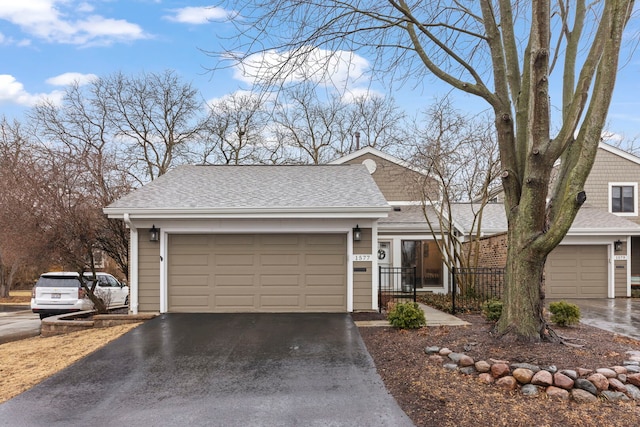 view of front of house featuring driveway, a garage, and roof with shingles