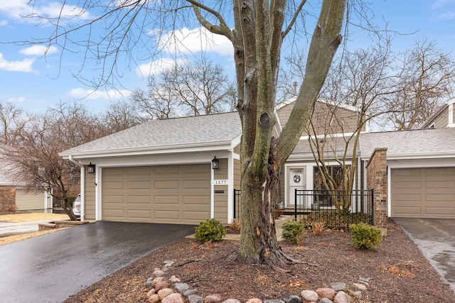 ranch-style home with a garage, aphalt driveway, and roof with shingles