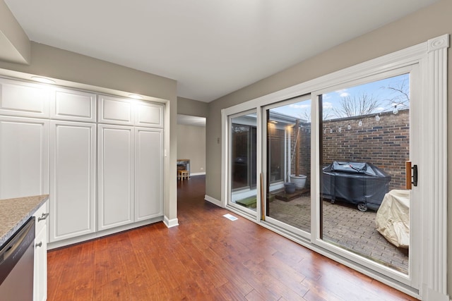 kitchen featuring wood finished floors, baseboards, white cabinets, light stone countertops, and dishwasher