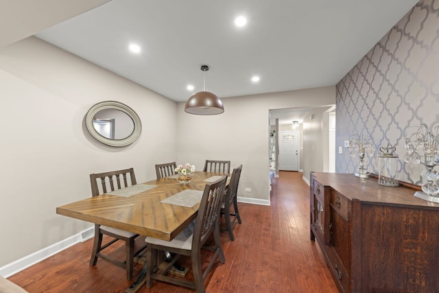 dining space featuring wallpapered walls, baseboards, dark wood finished floors, an accent wall, and recessed lighting