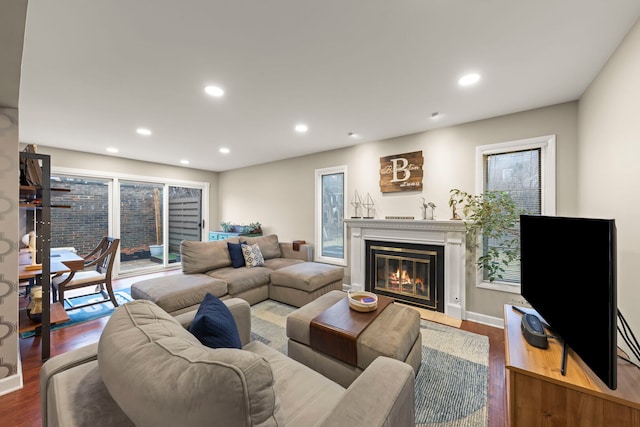 living area featuring a fireplace with flush hearth, wood finished floors, and recessed lighting