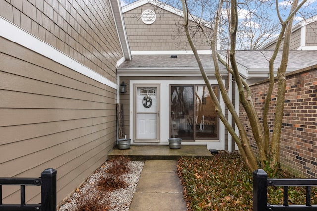 entrance to property featuring brick siding and roof with shingles