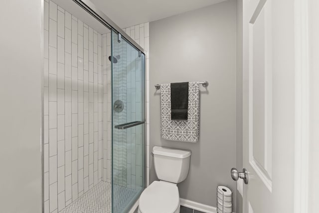 full bath with toilet, a stall shower, and baseboards