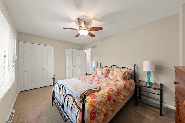 carpeted bedroom featuring multiple windows, two closets, and visible vents