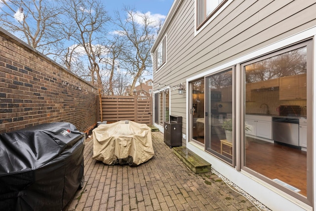 view of patio / terrace with a grill, a sink, and fence