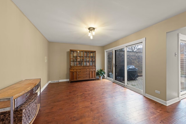 unfurnished room with baseboards, visible vents, and hardwood / wood-style floors