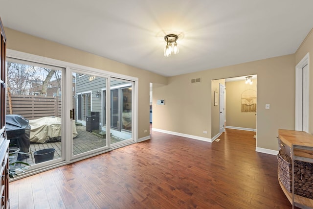 interior space with dark wood-style flooring, visible vents, and baseboards