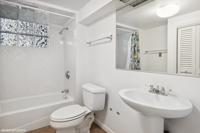 bathroom with toilet, a sink, baseboards, tile patterned floors, and shower / bath combo