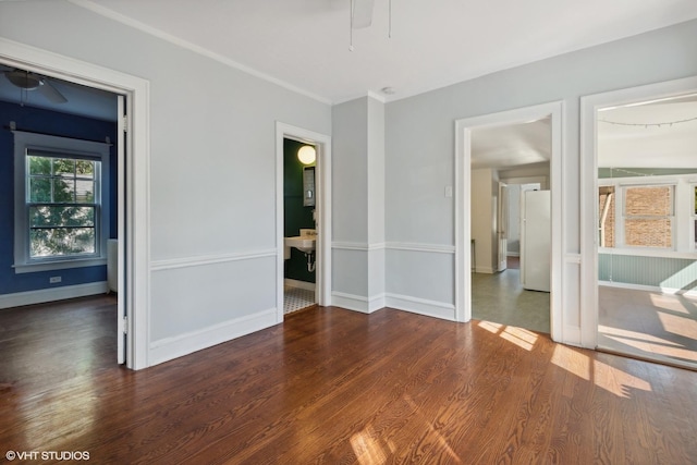 unfurnished room featuring ceiling fan, ornamental molding, dark wood finished floors, and baseboards