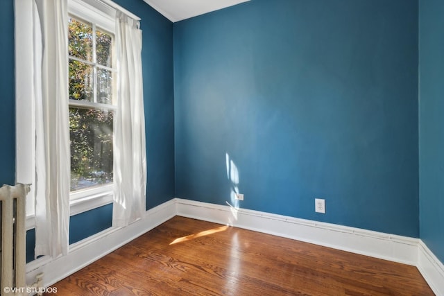 unfurnished room with baseboards and wood finished floors