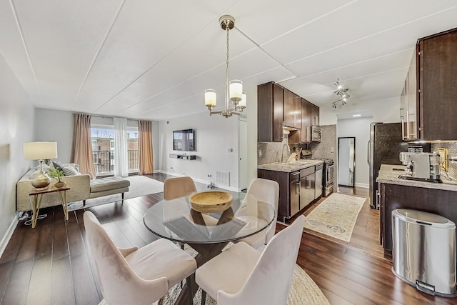 dining area with a chandelier, visible vents, dark wood finished floors, and baseboards