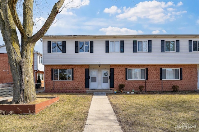 view of front of property with brick siding, a front yard, and fence