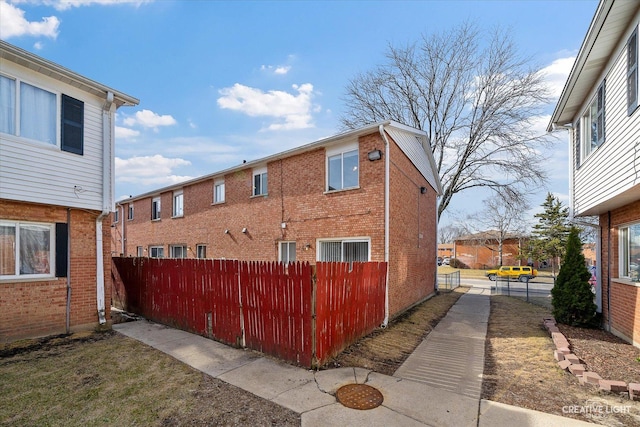 view of property exterior with brick siding and a fenced front yard