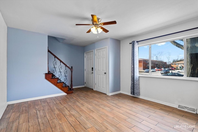 entrance foyer featuring stairway, a ceiling fan, wood finished floors, visible vents, and baseboards