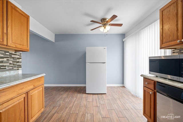 kitchen with a ceiling fan, stainless steel microwave, tasteful backsplash, freestanding refrigerator, and light wood-style floors