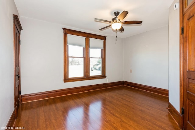 spare room featuring a ceiling fan, baseboards, and wood finished floors