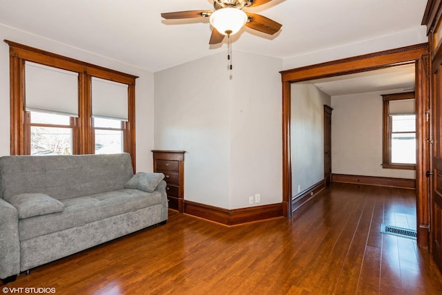 living room featuring ceiling fan, hardwood / wood-style floors, visible vents, and baseboards