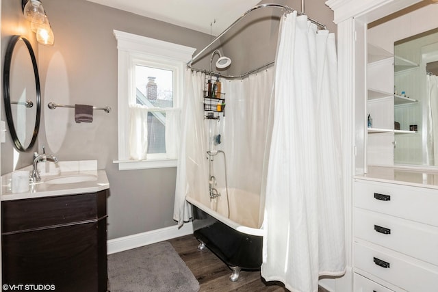 full bathroom with baseboards, shower / bath combo with shower curtain, wood finished floors, and vanity