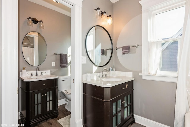 full bath featuring two vanities, a sink, and baseboards