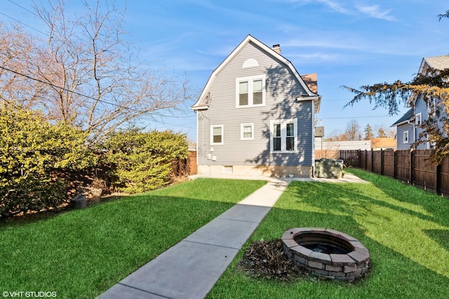 back of property with an outdoor fire pit, a gambrel roof, a fenced backyard, a chimney, and a yard