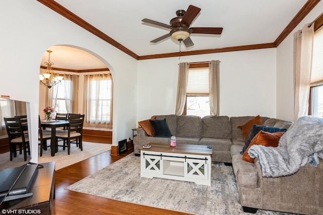 living room featuring arched walkways, ornamental molding, ceiling fan with notable chandelier, and wood finished floors