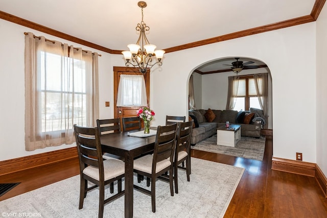 dining area featuring arched walkways, dark wood finished floors, and a wealth of natural light