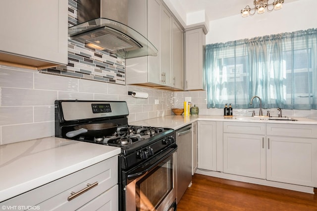 kitchen with dark wood finished floors, stainless steel appliances, backsplash, a sink, and exhaust hood